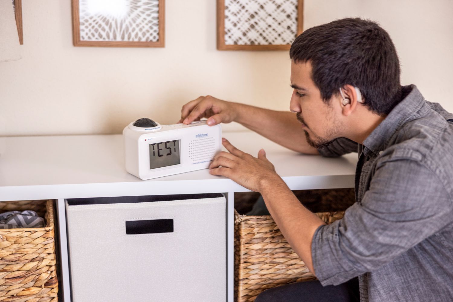Person wearing a hearing aid testing a vibrating fire alarm at home.